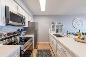Eine moderne Küche mit Edelstahlgeräten, weißen Schränken und einem gemusterten Teppich.