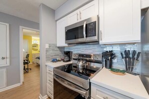 A modern kitchen with stainless steel appliances, white cabinetry, and a tiled backsplash. - 2-bedroom condo on Galveston Seawall. Steps to the beach (Galveston)