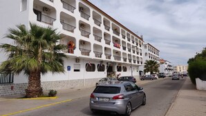 A multi-story hotel with balconies, a parking area, and a palm tree. - Turcongel Apartamentos Turisticos (Castro Marim)