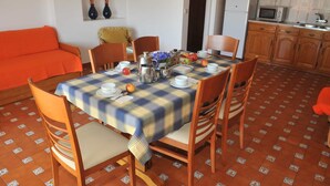 A dining area with a checkered tablecloth, wooden chairs, and a tiled floor. - Turcongel Apartamentos Turisticos (Castro Marim)