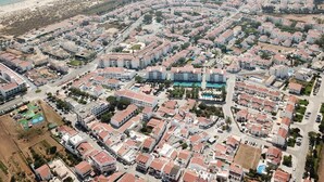 An aerial view of a residential area with multiple buildings, roads, and a beach in the background. - Turcongel Apartamentos Turisticos (Castro Marim)
