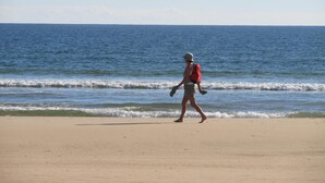 A person walking on a sandy beach with the ocean in the background. - Turcongel Apartamentos Turisticos (Castro Marim)