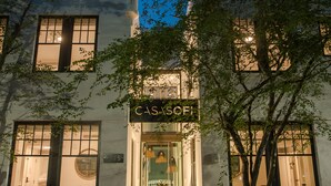A building with a sign reading "CASA SOFI" at the entrance, featuring a staircase and a tree in front.