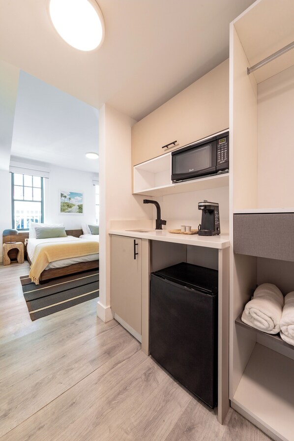 Una kitchenette compacta equipada con microondas, cafetera y un refrigerador pequeño.