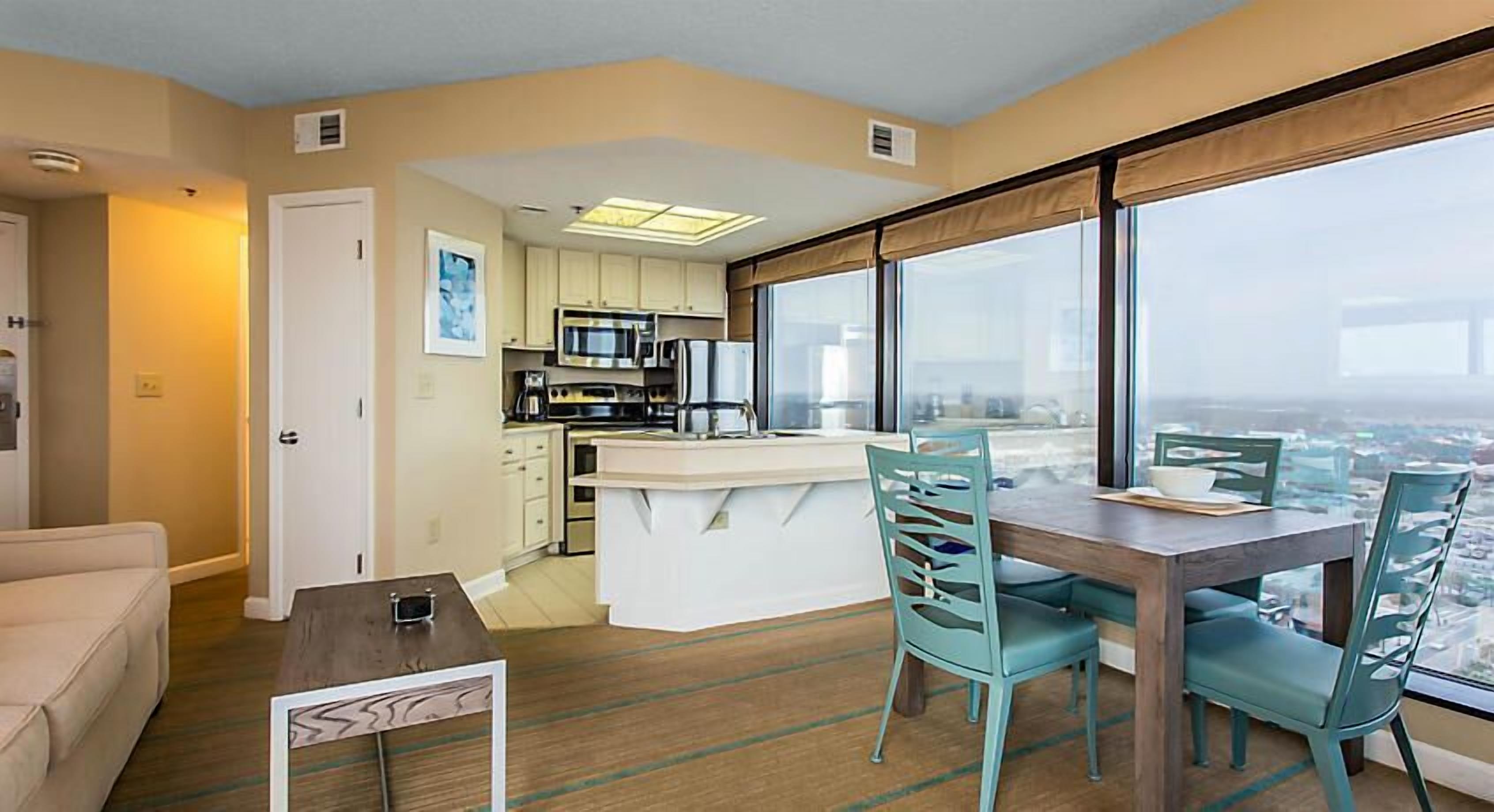 Un apartamento moderno con cocina, comedor y grandes ventanales con vistas a la ciudad.