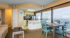 Un appartement moderne doté d’une cuisine, d’un coin repas et de grandes fenêtres offrant une vue sur la ville.