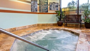 A hot tub with a metal railing, surrounded by stone tiles and potted plants. Warning signs are visible on the wall. - Ocean Front resort next to Myrtle Beach Sky Wheel! (Myrtle Beach)