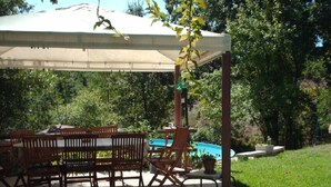 Une terrasse extérieure avec une table et des chaises, un espace abrité et une piscine.