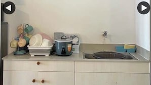 Een keuken met een spoelbak, een fornuis en een afdruiprek. Aan de muur boven het aanrecht hangt een schilderij van een kustlandschap.