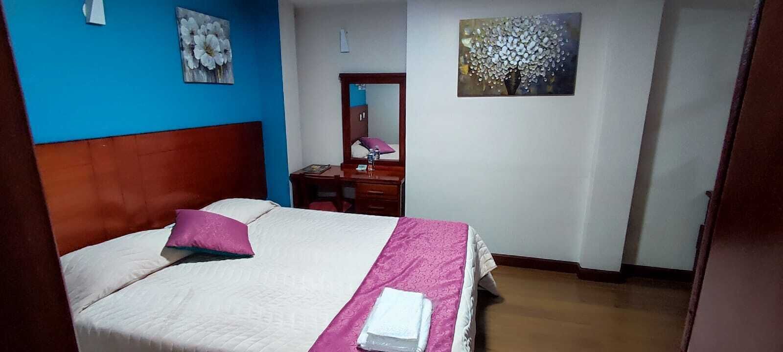 A bedroom with a bed, a nightstand, a mirror, and two wall art pieces.