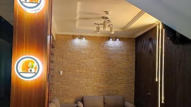 A modern living room with a wooden accent wall, a patterned wall, and a ceiling light fixture. - Hotel Villonaco (Loja)