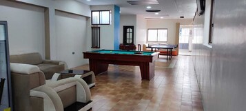 Una habitación con mesa de billar, sofá y mesa de ping pong.