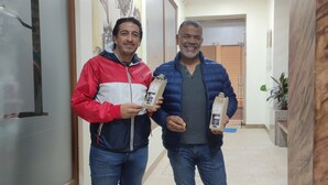 Two people standing in a hallway holding small packages. - Hotel Villonaco (Loja)