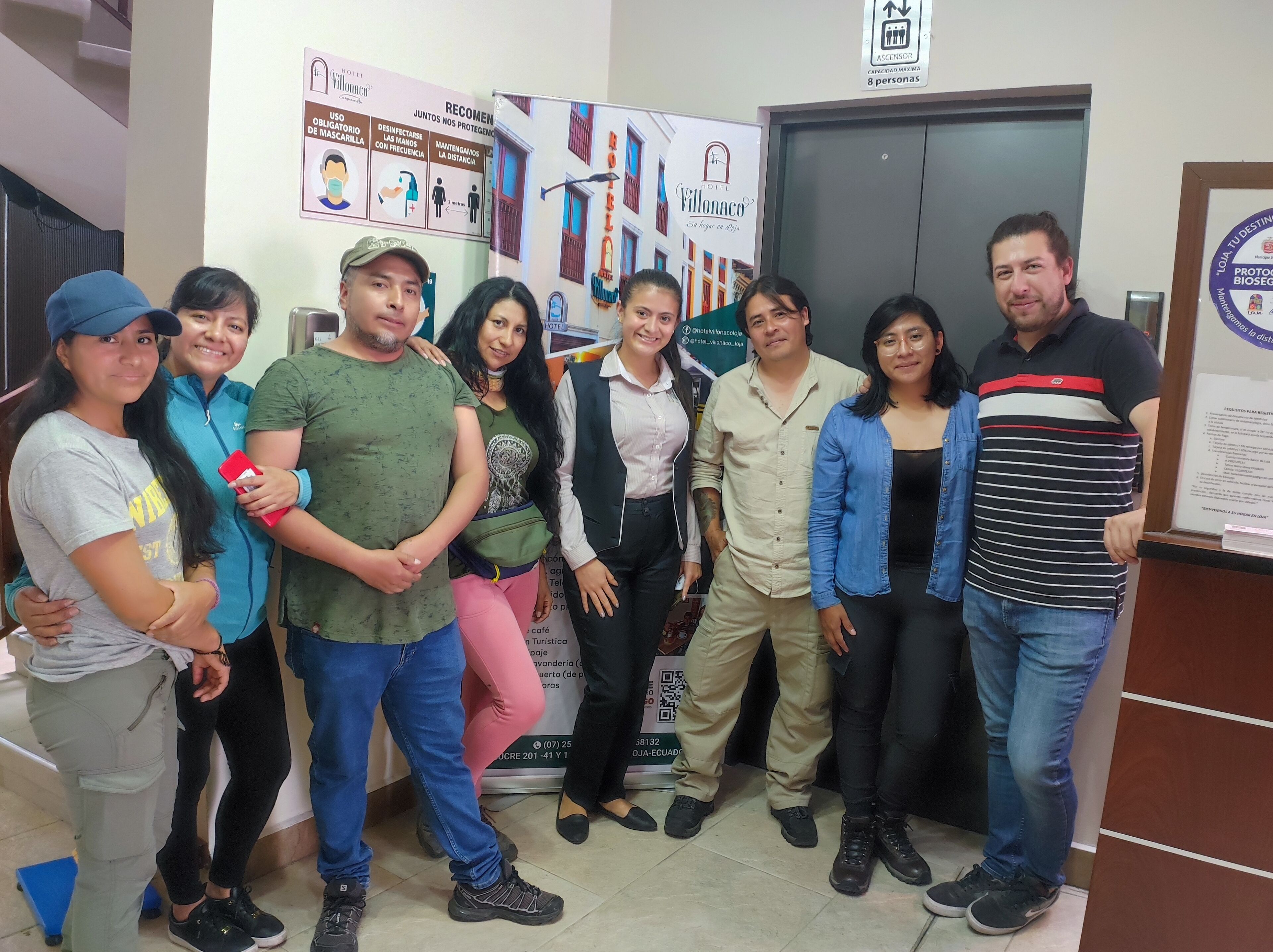 A group of people standing in a lobby with informational posters and a reception desk.