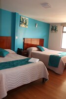 Una habitación de hotel con dos camas, cabeceros de madera, ropa de cama azul aguamarina y blanca, y obras de arte en las paredes.