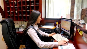 A receptionist at a desk with a computer, a telephone, and a book. - Hotel Villonaco (Loja)