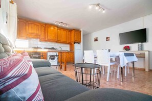 A compact living space with a kitchenette, a dining area, and a seating area with a sofa and chairs.