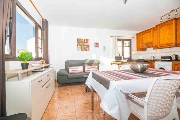 A compact kitchen with a dining area, a sofa, and a small table.