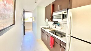 A kitchen with a refrigerator, microwave, and stove. - Seahorse Beach + Ocean Park + Parking (San Juan)