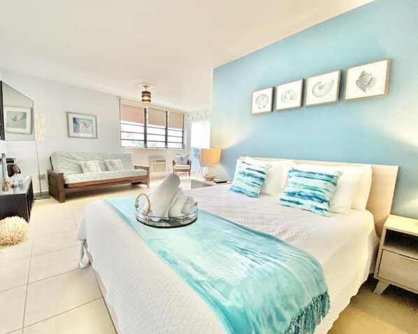 A modern bedroom with a large bed, a sofa, and a wall with framed artwork.