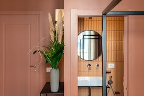 A bathroom with a pink door, a round mirror, a white sink, and a potted plant. - Boutique Centrale Sant'Andrea (Milan)