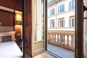 A hotel room with a bed, a bedside lamp, and a view of a balcony with a railing and buildings in the background. - Boutique Centrale Sant'Andrea (Milan)