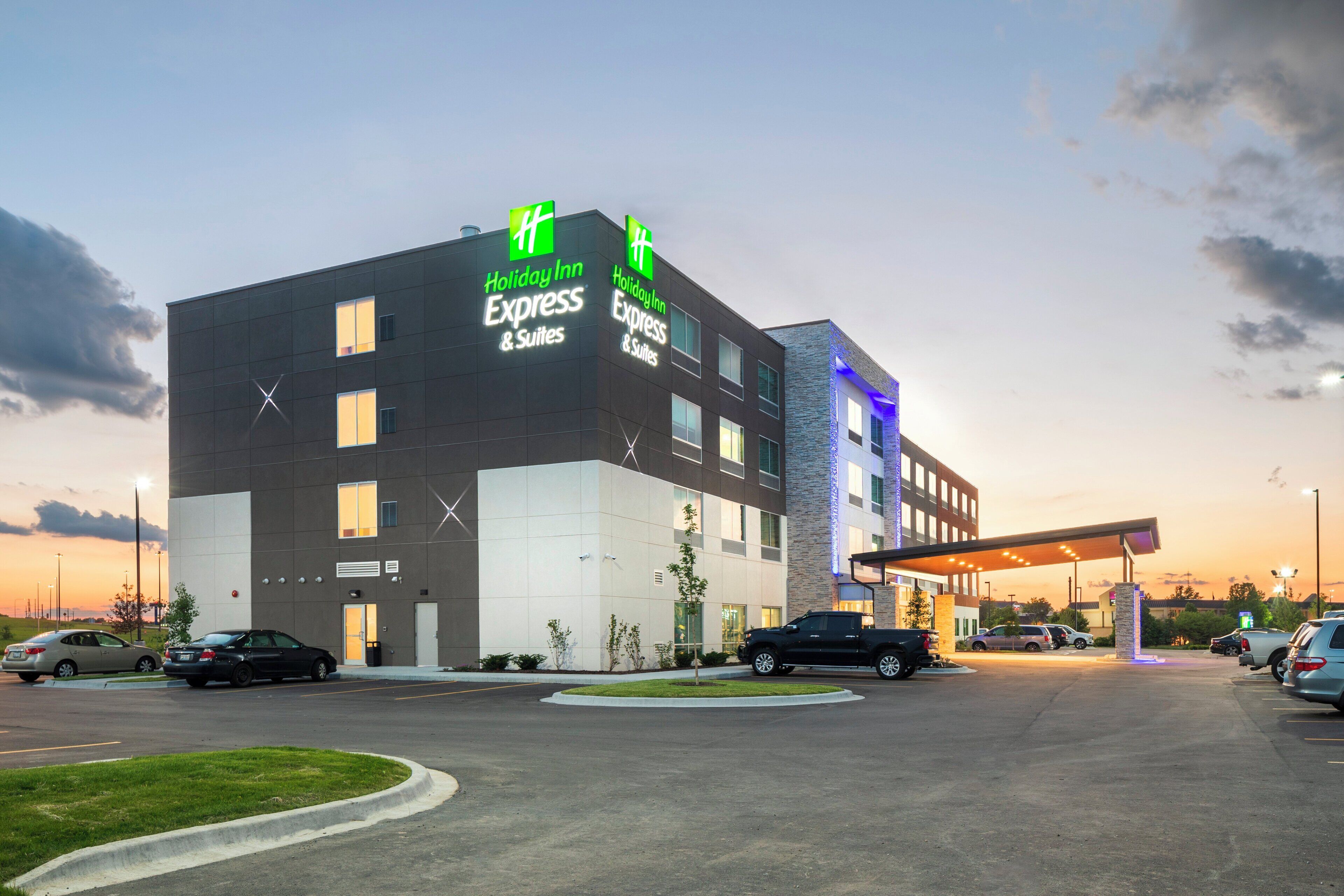 A Holiday Inn Express & Suites hotel with a modern design, multiple parking spaces, and a well-lit entrance.