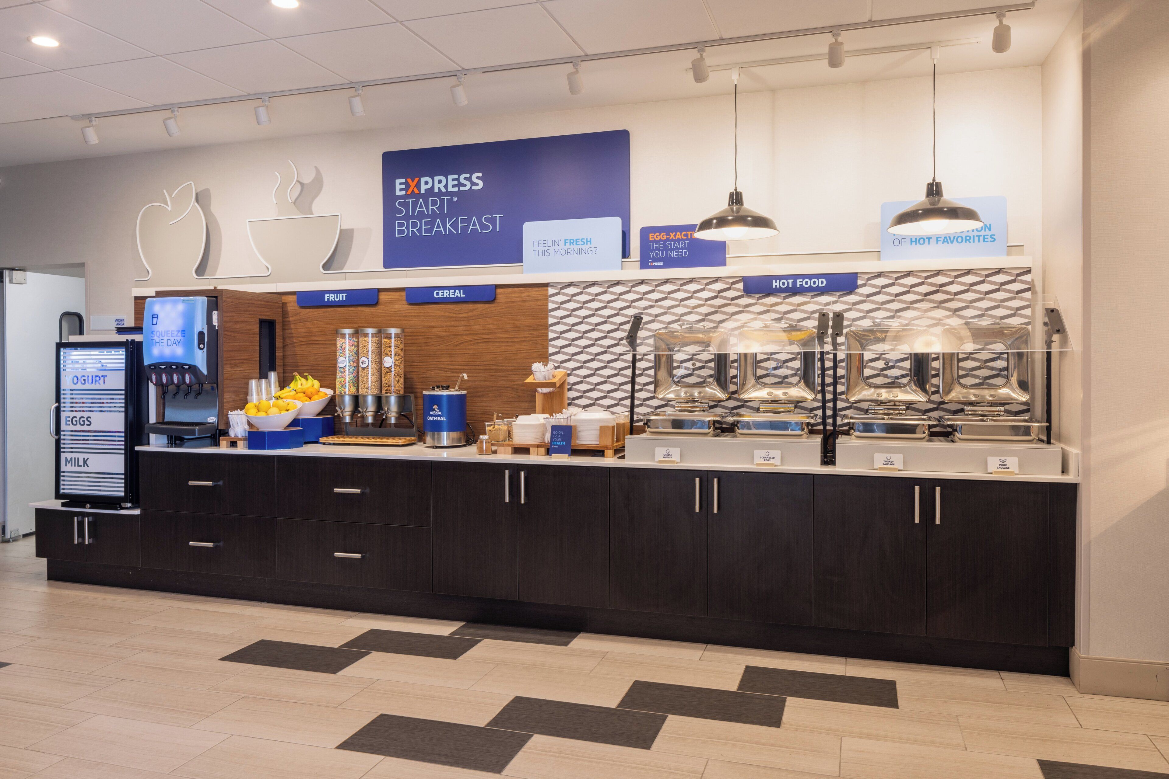 A breakfast station with labeled sections for fruit, cereal, and hot food, along with a digital display and a coffee machine.