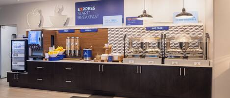 A breakfast station with labeled sections for fruit, cereal, and hot food, along with a digital display and a coffee machine.