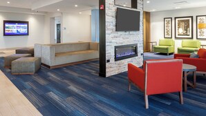 A modern lounge area with a flat-screen TV, seating arrangements, and a stone accent wall. - Holiday Inn Express & Suites Bourbonnais East - Bradley by IHG (Bourbonnais)