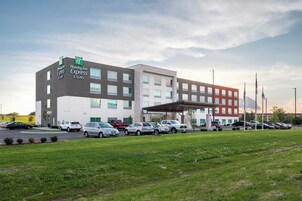 Un hotel Holiday Inn Express & Suites con un estacionamiento y un área verde al frente.
