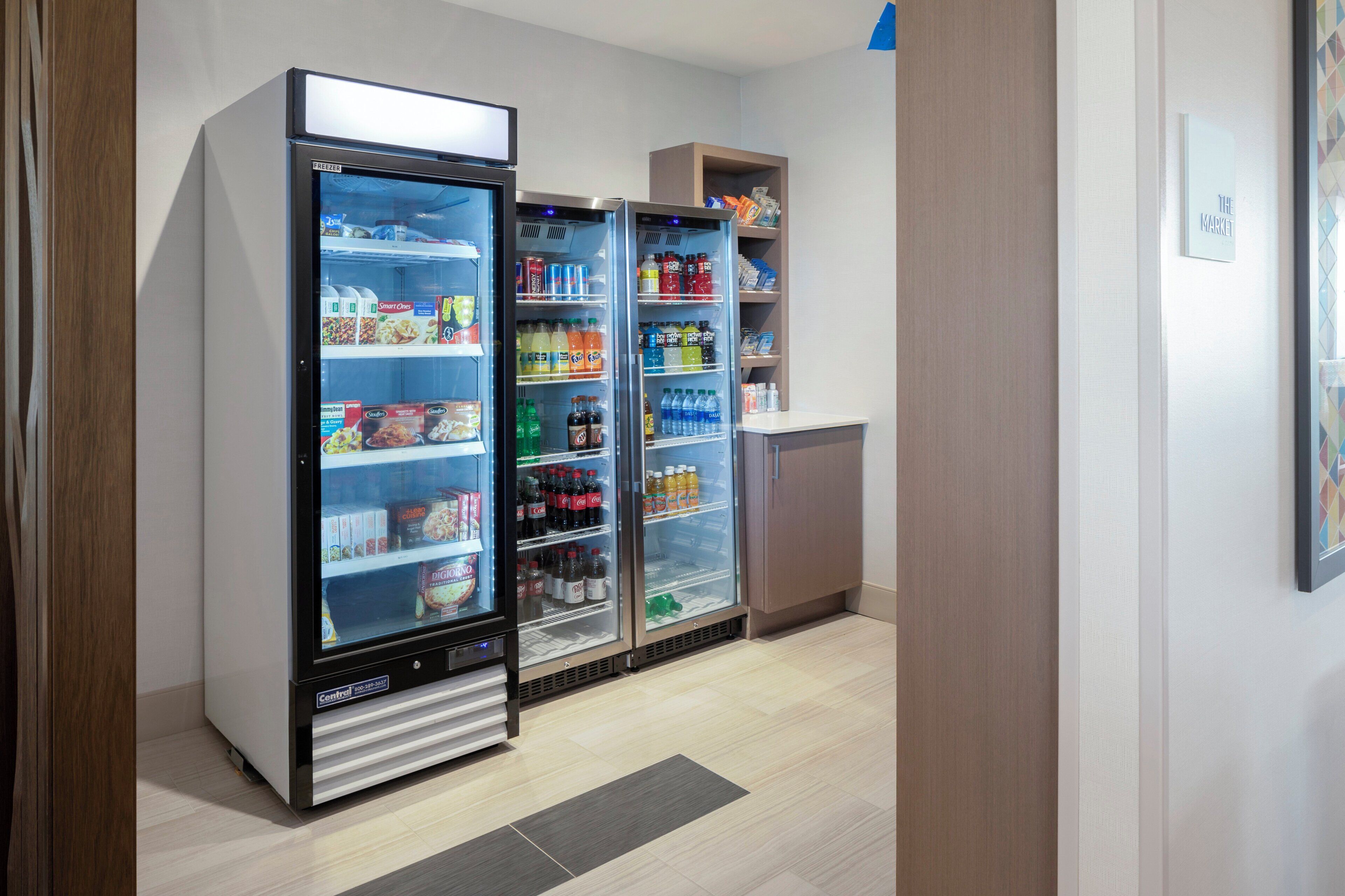 A kitchenette area with a refrigerator stocked with beverages and food items, a microwave, and a small cabinet.