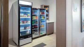 A kitchenette area with a refrigerator stocked with beverages and food items, a microwave, and a small cabinet.