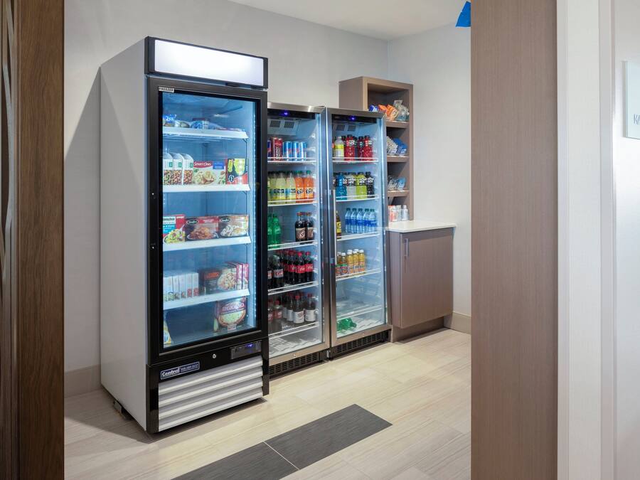 A kitchenette area with a refrigerator stocked with beverages and food items, a microwave, and a small cabinet.