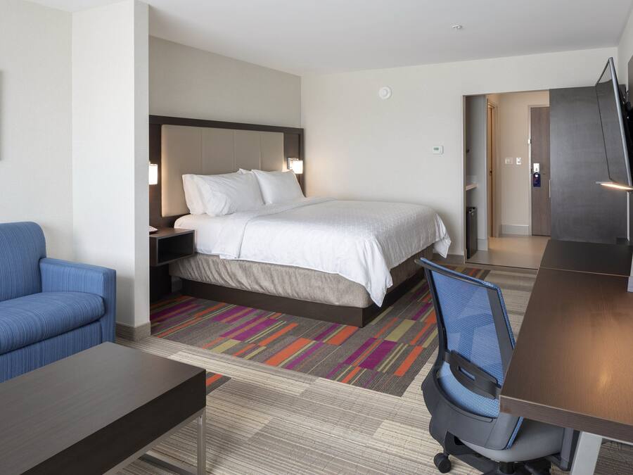 A hotel room with a bed, a blue sofa, a desk, and a TV.