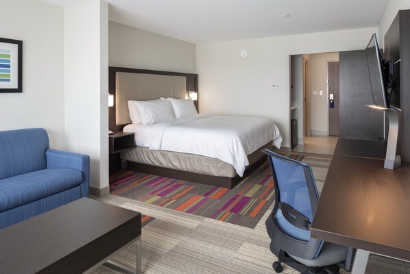 Une chambre d’hôtel avec un lit, un canapé bleu, un bureau et une télévision.