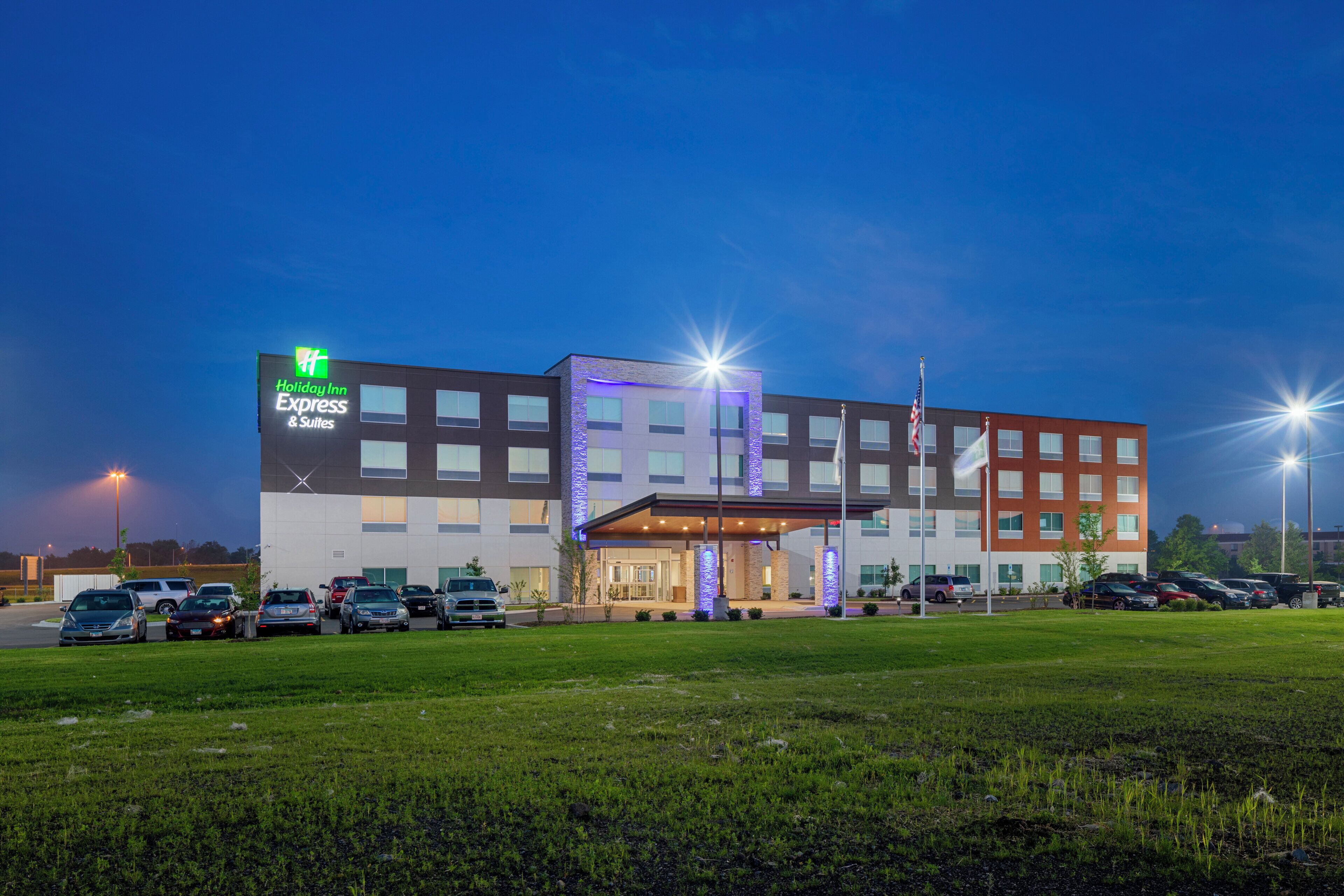 A Holiday Inn Express & Suites hotel with a parking lot and a grassy area in front.