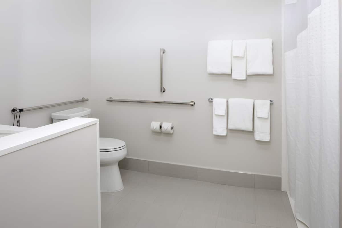 Ein modernes Badezimmer mit Toilette, Bidet und Haltegriffen.
