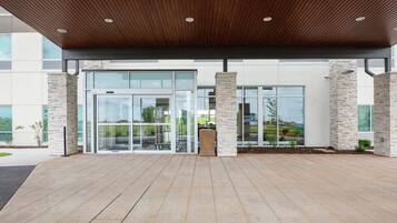 A modern building entrance with a wooden ceiling, glass doors, and stone pillars.