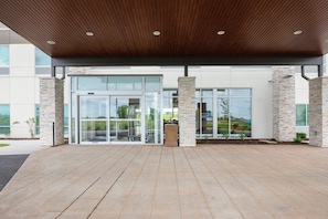 A modern building entrance with a wooden ceiling, glass doors, and stone pillars. - Holiday Inn Express & Suites Bourbonnais East - Bradley by IHG (Bourbonnais)