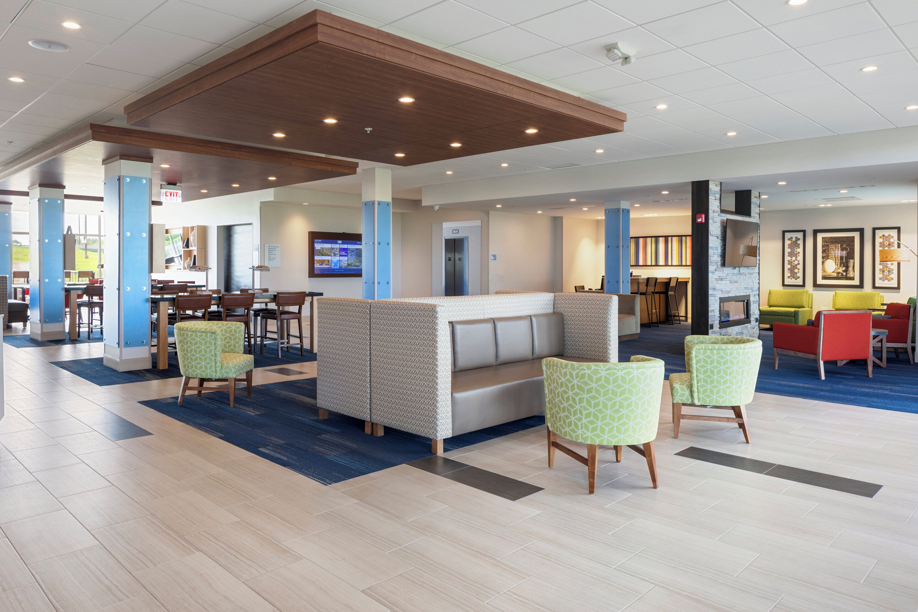 A hotel lobby with a seating area, a reception desk, and a dining area.