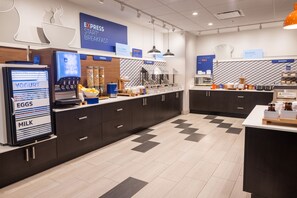 Un espace moderne dédié au petit-déjeuner, équipé d'un distributeur de yaourts, d'un présentoir de céréales et d'un rayon de produits de boulangerie.