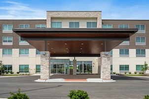 A modern building with a covered entrance, stone pillars, and a flat roof.