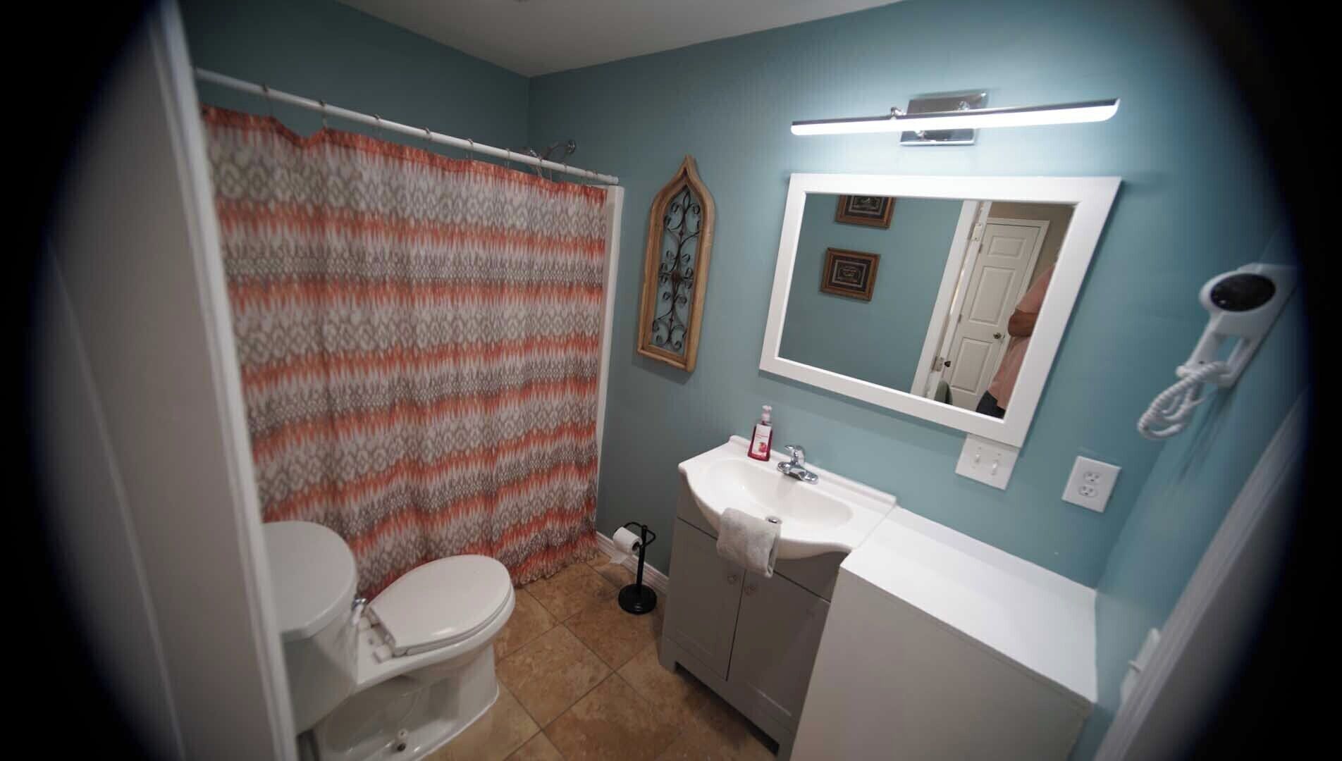 A bathroom with a toilet, sink, and shower curtain.
