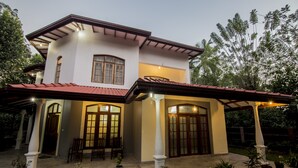 A two-story house with a covered patio, columns, and potted plants. - Kandy Eco Paradise (Kandy)
