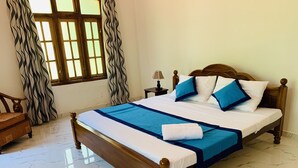 A neatly made bed with a blue and white bedspread, a wooden headboard, and a nightstand with a lamp. - Kandy Eco Paradise (Kandy)