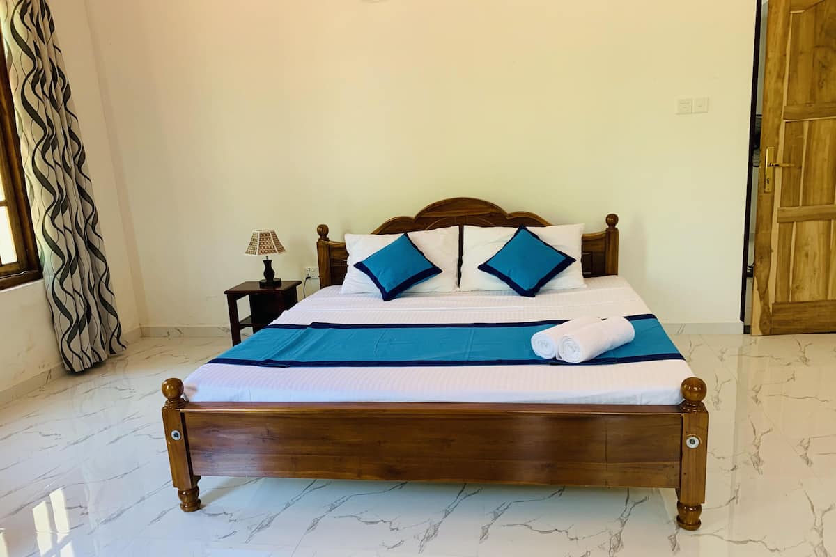 A neatly made bed with a wooden headboard, a blue bedspread, and two pillows with blue trim.