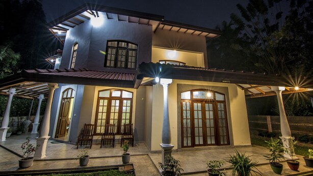 A two-story house with a covered patio area, large windows, and potted plants. - Kandy Eco Paradise (Kandy)