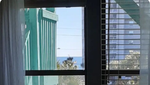 Una stanza con una finestra che dà su un edificio verde e una strada.