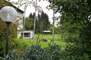 A garden with a lawn, a white building, and a gazebo. - Montana Landhotel Gummersbach Nord (Marienheide)